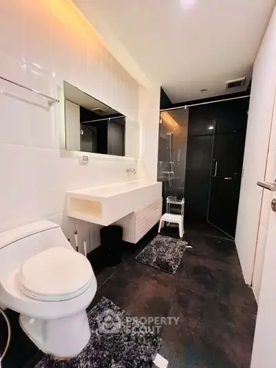 Modern bathroom with sleek design, featuring a glass shower and contemporary fixtures.