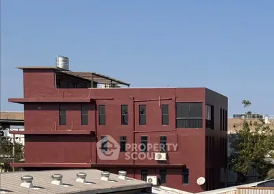 Modern red building exterior with flat roof and multiple windows, showcasing urban architecture.