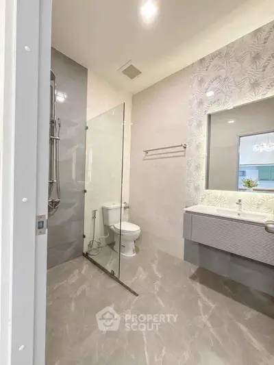 Modern bathroom with glass shower, elegant tiles, and stylish vanity.