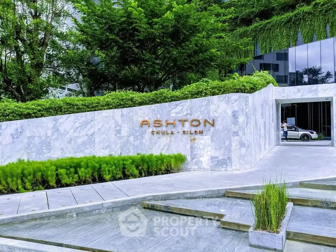 Luxurious entrance of Ashton Chula Silom with modern architecture and lush greenery