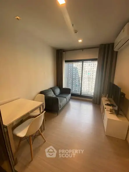 Modern living room with city view, cozy sofa, and sleek TV setup.