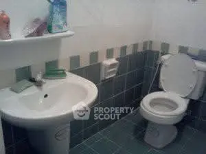 Compact bathroom with modern sink and toilet, featuring teal tile accents.