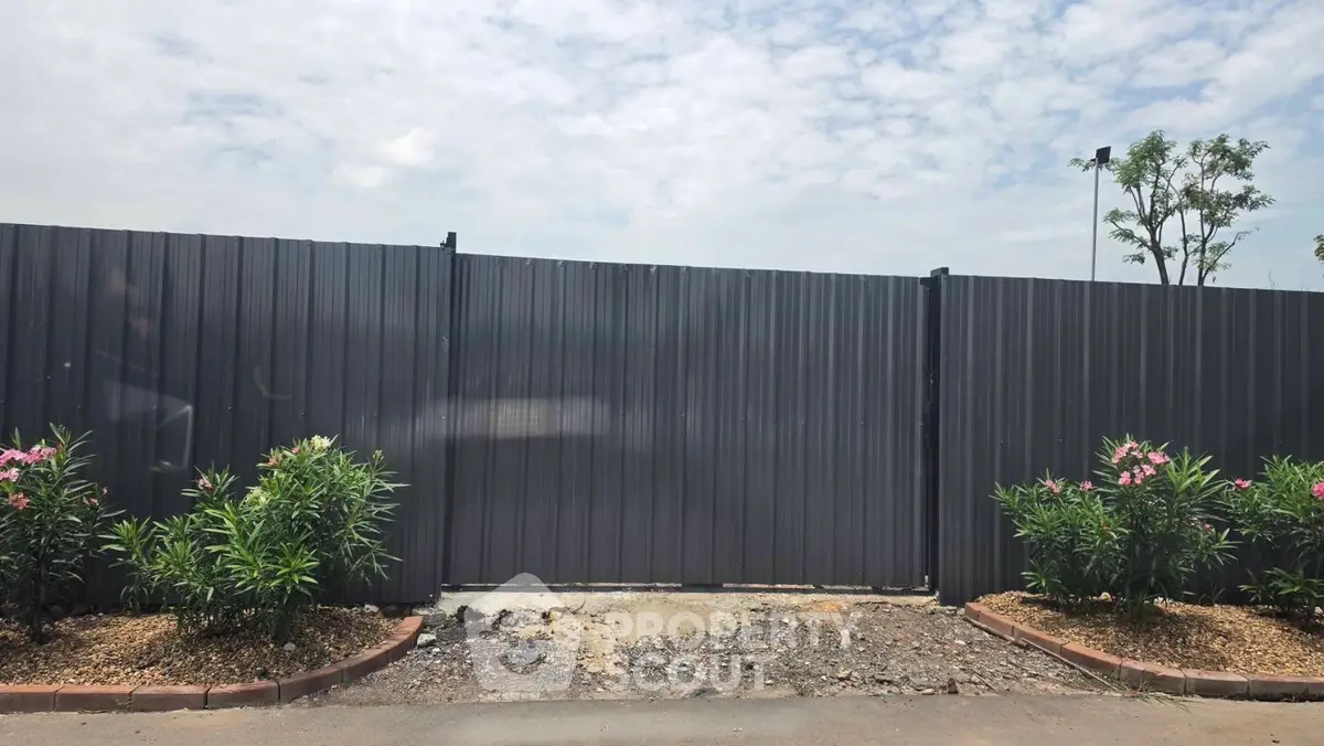 Secure gated entrance with metal fencing and landscaped greenery