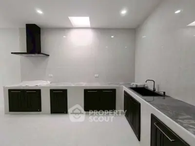 Modern kitchen with sleek black cabinets and marble countertops in a spacious layout.