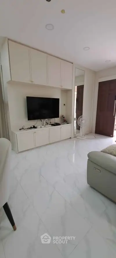 Modern living room with sleek white cabinetry and marble flooring