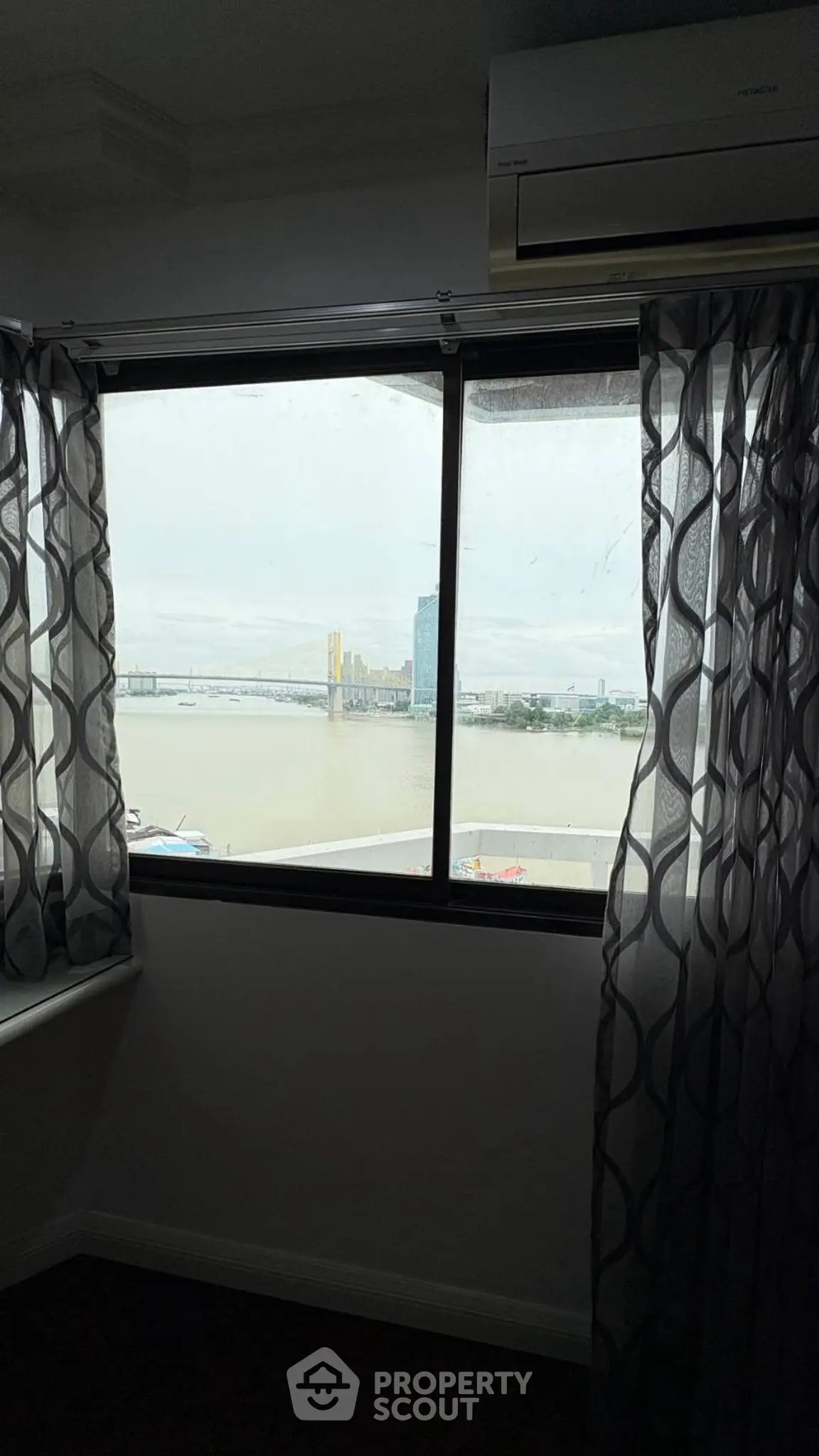 Stunning river view from a modern apartment window with elegant curtains.