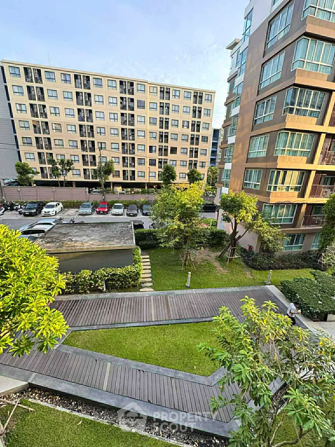 Modern apartment complex with lush garden and wooden pathways, offering serene urban living.