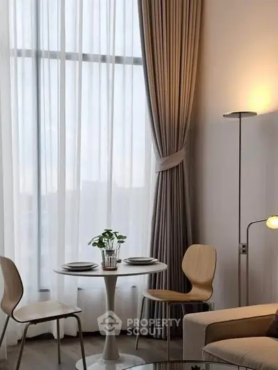 Modern living room with elegant floor-to-ceiling curtains and cozy dining area.