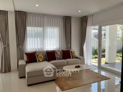 Modern living room with elegant sofa, large windows, and garden view, perfect for relaxation and entertaining.