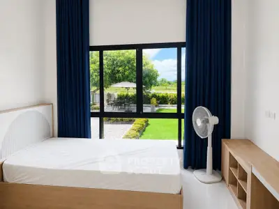 Bright bedroom with large window overlooking garden, featuring modern furniture and serene ambiance.