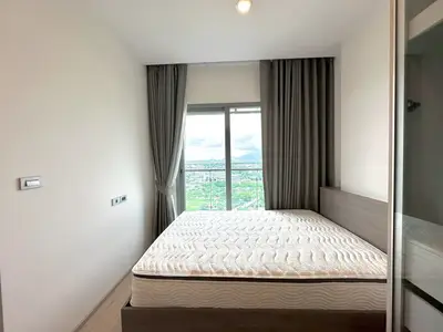 Modern bedroom with large window offering stunning city view, featuring sleek design and ample natural light.