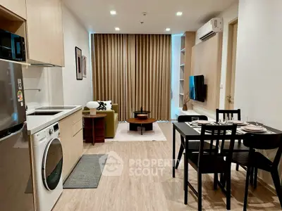 Modern open-plan living room with kitchen, featuring sleek furniture and stylish decor.