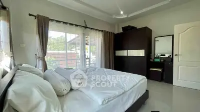 Spacious bedroom with large windows and modern furnishings in a serene setting.