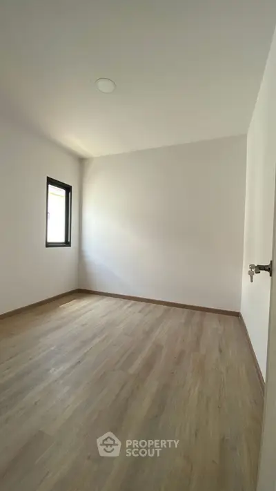 Spacious empty bedroom with wooden flooring and natural light