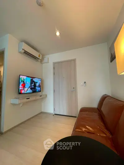 Modern living room with leather sofa and wall-mounted TV in cozy apartment.