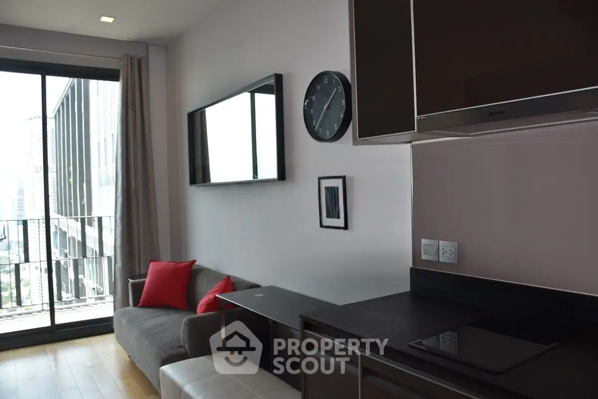 Modern living room with sleek kitchen and large balcony view in urban apartment.