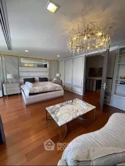 Luxurious bedroom with elegant chandelier and marble accents, featuring spacious layout and stylish decor.