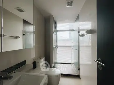 Modern bathroom with glass shower and sleek fixtures in contemporary apartment.