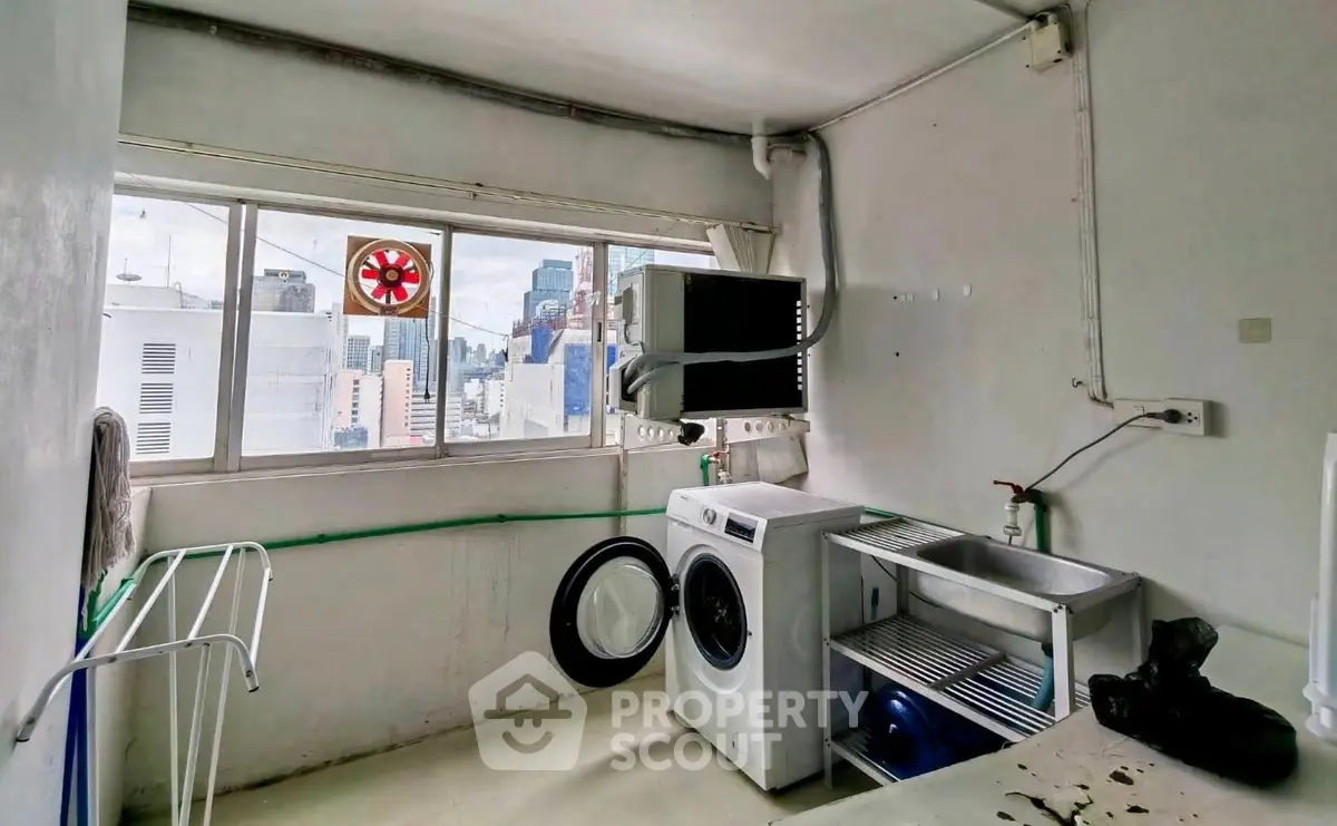 Urban laundry room with city view, featuring washing machine and utility sink.