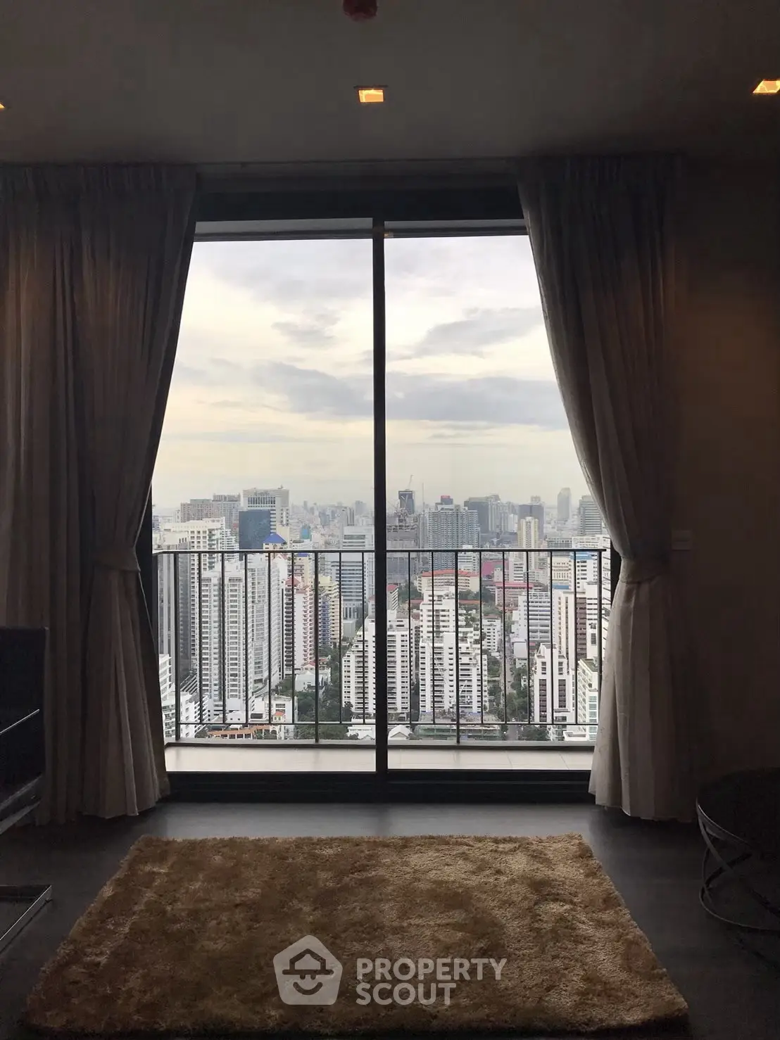 Stunning cityscape view from a modern high-rise apartment with floor-to-ceiling windows.