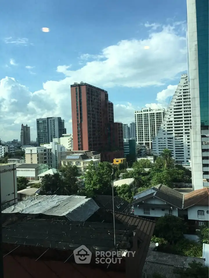 Stunning cityscape view from a high-rise building window showcasing urban skyline and lush greenery.