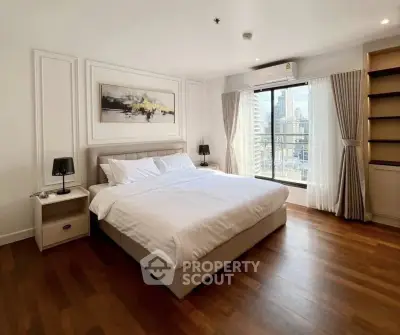 Spacious bedroom with city view, elegant decor, and natural light in modern apartment.