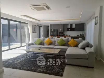 Spacious modern living room with open kitchen and pool view, featuring stylish decor and ample natural light.