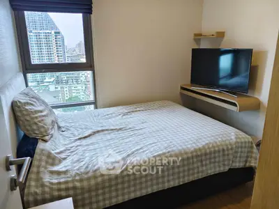 Cozy bedroom with city view, featuring a comfortable bed and wall-mounted TV, perfect for urban living.