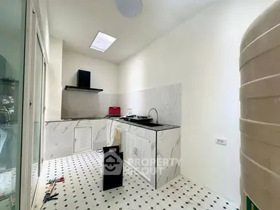 Modern kitchen with sleek marble countertops and stylish black and white tile flooring.
