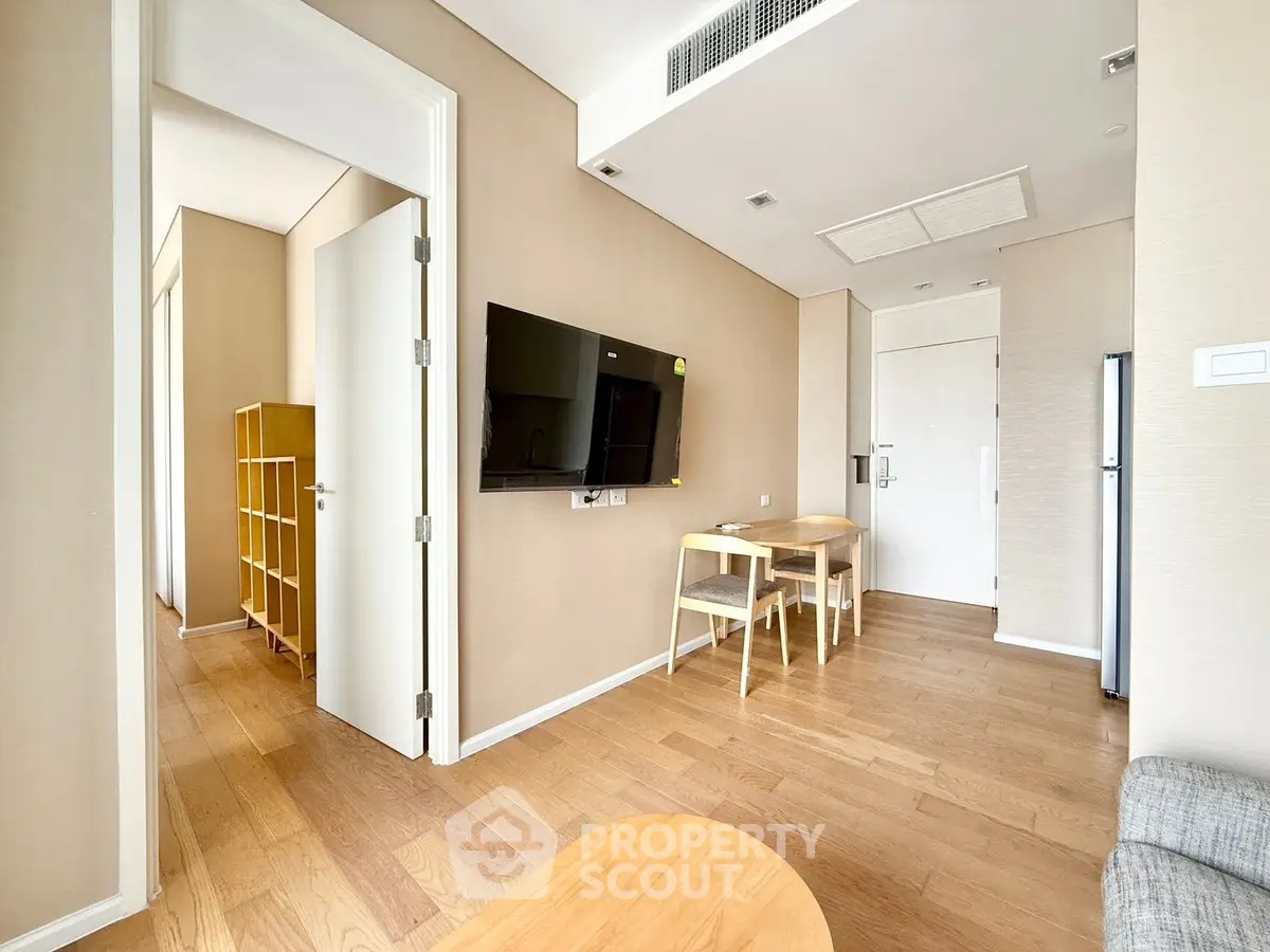 Modern living room with wooden flooring and wall-mounted TV in a cozy apartment