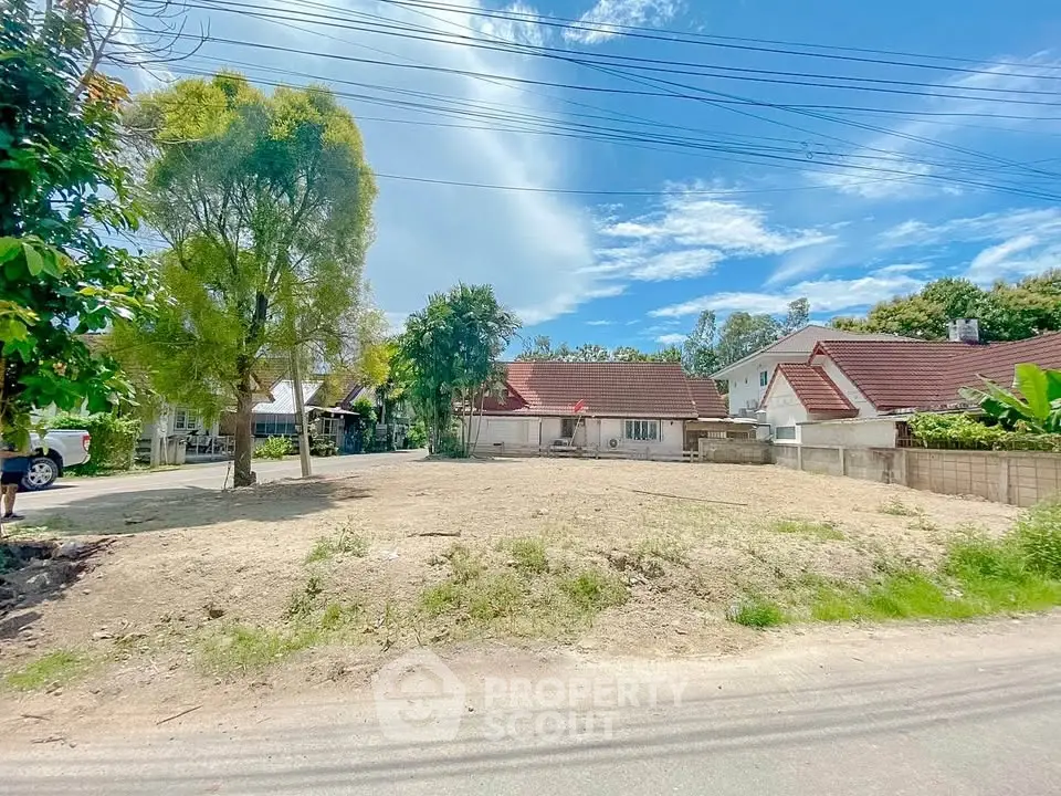 Spacious residential plot with clear skies and surrounding houses, ideal for development.