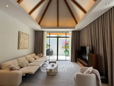 Luxurious living room with vaulted ceiling and elegant decor, opening to a serene outdoor space.