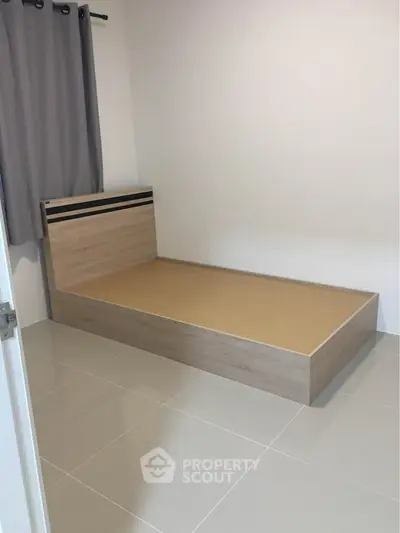 Minimalist bedroom with single bed frame and tiled flooring, perfect for modern living.