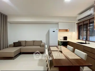 Modern living room with open kitchen, featuring sleek furniture and natural light.