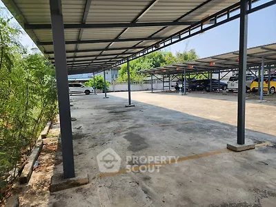 Spacious covered parking area with multiple parking slots and greenery around.