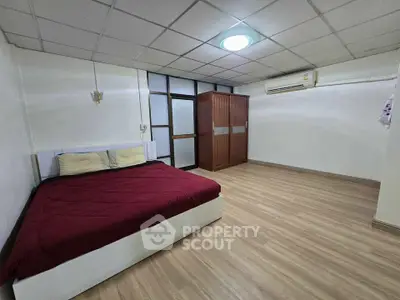 Spacious bedroom with modern design and wooden flooring, featuring a comfortable bed and ample storage space.