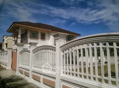 Elegant two-story house with white fence and spacious yard under a clear blue sky.