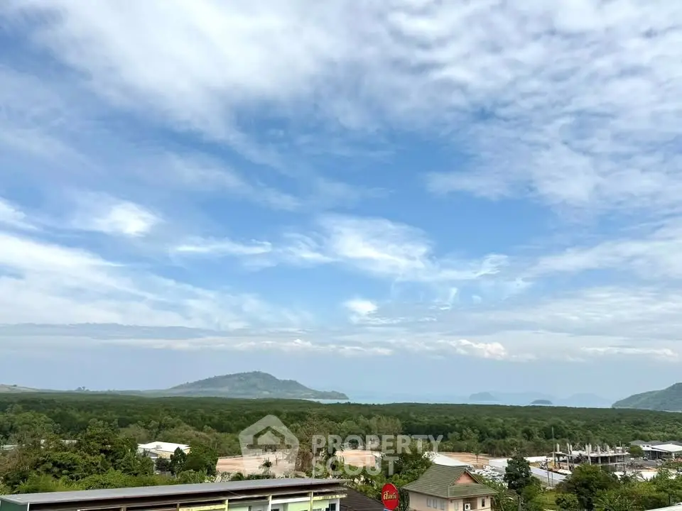 Stunning panoramic view of lush greenery and distant mountains under a vibrant blue sky, perfect for serene living.