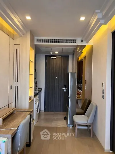 Modern apartment interior with open kitchen and washing machine, featuring sleek wooden flooring and stylish lighting.