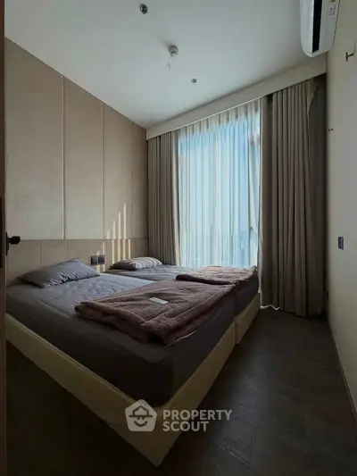Cozy bedroom with twin beds and large window offering natural light.
