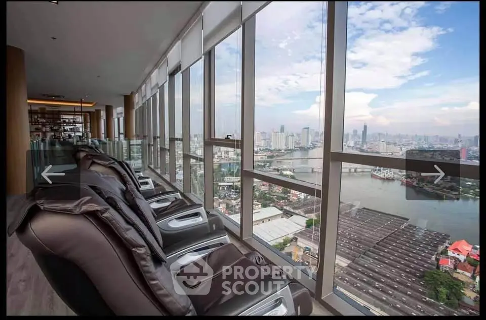 Luxurious high-rise view with massage chairs overlooking city skyline and river.