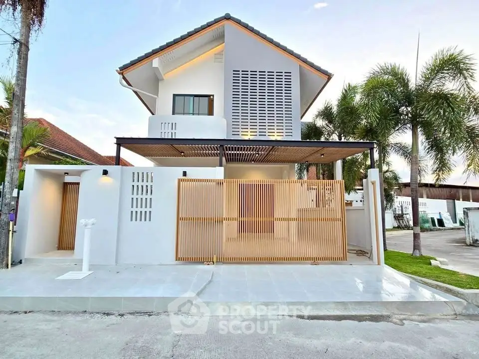 Modern two-story house with sleek design and spacious driveway in a tropical setting.