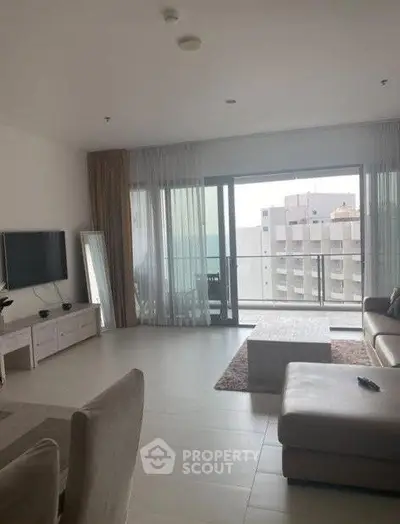 Spacious modern living room with balcony and city view in high-rise apartment.