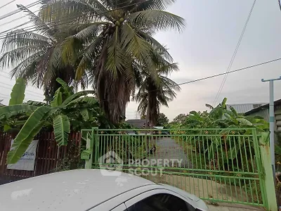 Charming tropical property entrance with lush greenery and secure gate access.