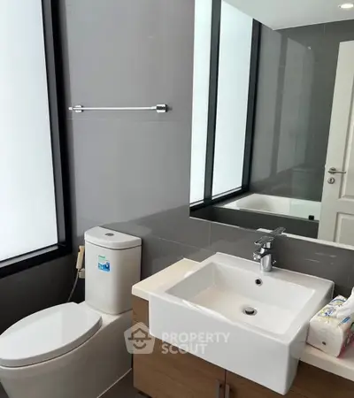 Modern bathroom with sleek fixtures and large mirror in a contemporary home.