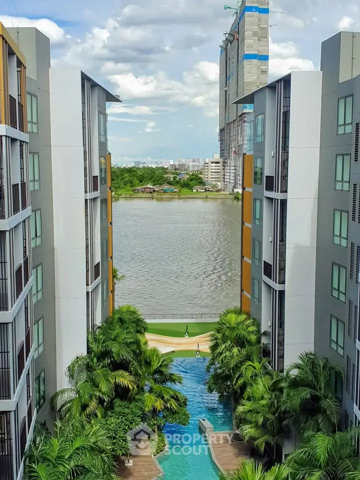 Stunning riverside apartment complex with lush greenery and inviting pool, offering serene views and modern living.