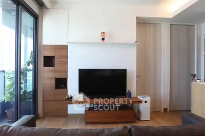Modern living room with sleek wooden furniture and large TV, featuring a balcony view.