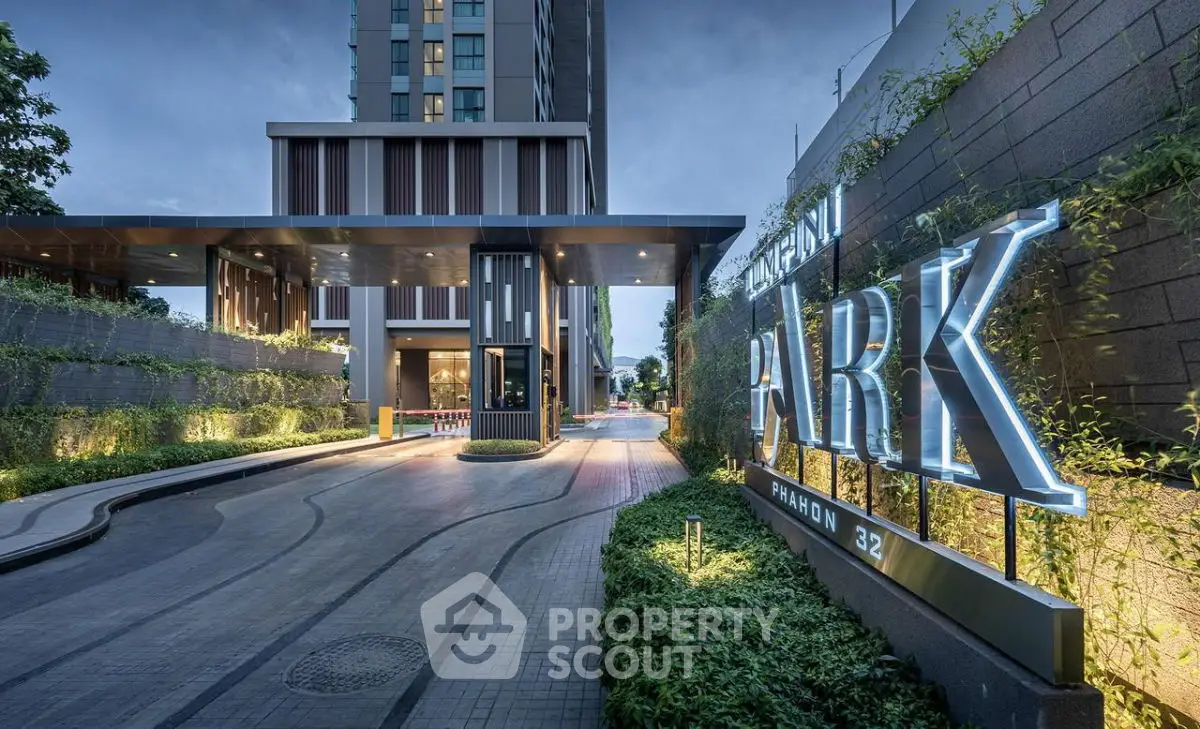 Luxurious modern building entrance with lush greenery and elegant signage.