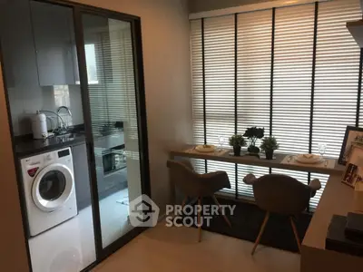 Modern apartment with compact kitchen and dining area featuring washing machine and stylish decor.