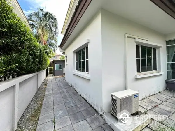 Charming home exterior with lush greenery, featuring a well-maintained pathway and modern air conditioning unit, nestled in a serene neighborhood.